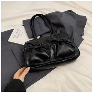 Details einer schwarzen matten Ledertasche mit schicken Schleifen und zwei Vordertaschen