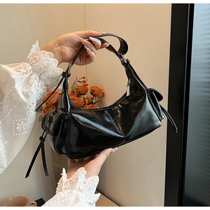 Detailansicht der schwarzen Lackledertasche mit Fransen und seitlichen Taschenelementen