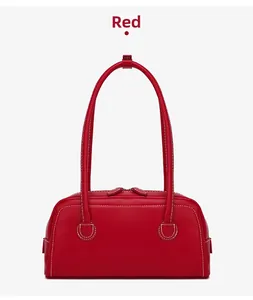 Close-up of red leather Boston bag featuring distinct white contrast stitching and long straps