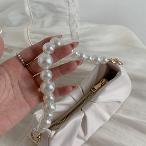 Detailed macro view of the pearl beaded handle on a beige pleated cloud handbag