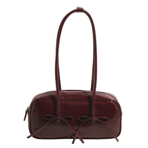Detail of burgundy patent leather shoulder bag featuring ribbon bows and glossy finish
