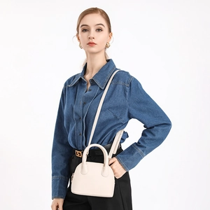 Detailed view of a chic beige shell handbag with textured leather and gold hardware