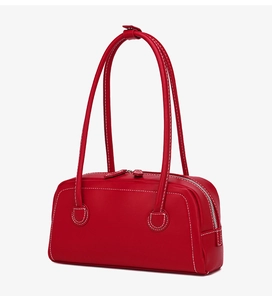 Detail view of red leather boston bag with white contrast stitching and long handles
