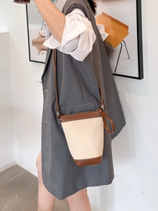 Detail of canvas bucket bag showing contrast leather stitching and metal zipper