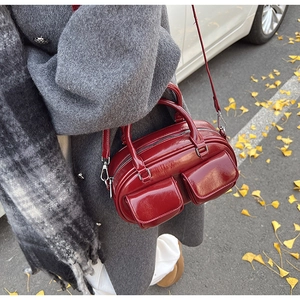 Deep red oil wax leather Boston bag shown on model with silver hardware detail
