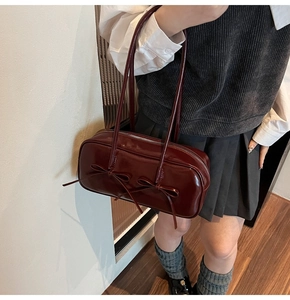 Gros plan du sac à main bordeaux en cuir verni avec nœuds et finition brillante