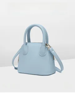 Detailed macro view of light blue shell handbag featuring textured lychee grain leather