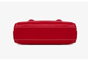Detail view of red leather bag bottom featuring contrasting white stitching and studs
