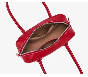 Detail view of red leather handbag showing inner pockets and white contrast stitching