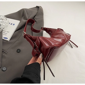 Close-up of deep red leather shoulder bag with side tassels and silver hardware detail