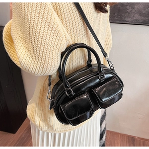 Detail of vintage black oil wax leather boston bag with dual front pockets and glossy texture