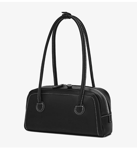Close-up of black Boston bag with contrasting white stitching and long shoulder handles
