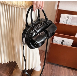 Detail of black oil wax leather bowling bag featuring front pockets and polished finish