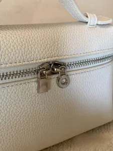 Makro-Detail der silbernen Doppelreißverschlüsse auf weißer Tasche mit Kieselleder