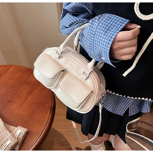 Detail view of cream-white wax leather bag with double front flap pockets and silver hardware