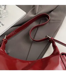 Detailed close-up of glossy dark red leather shoulder strap and silver hardware accents