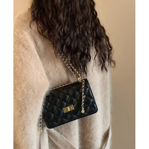 Sac bandoulière matelassé noir avec chaîne dorée porté par un mannequin chic