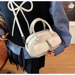 Model showing cream leather Boston bag with double front pockets and silver hardware