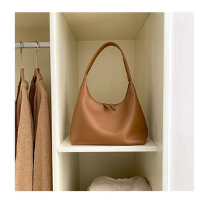 Detailansicht der kamelfarbenen Hobo-Tasche mit Reißverschluss in einem Kleiderschrank