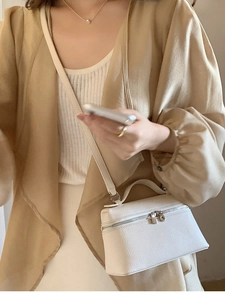 Details einer weißen Mini-Box-Tasche aus strukturiertem Leder mit silbernen Beschlägen