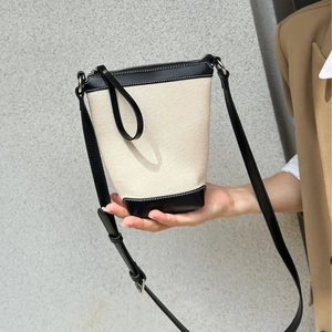 Chic canvas bucket bag with black leather trim and adjustable crossbody strap for women