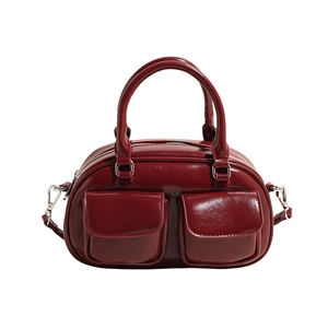 Detail of burgundy waxed leather bag featuring shiny finish and front double pockets