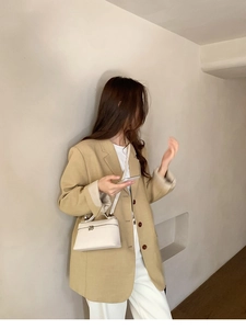 Minimalistische weiße Umhängetasche kombiniert mit beigem Blazer für modernen Look