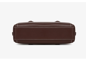Detail view of the bottom construction and white contrast stitching of dark brown leather bag