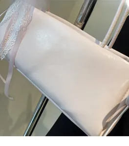 Detailed macro view of white glossy shoulder bag featuring delicate pink lace ribbon bow