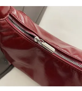 Detail of silver metal zipper on vintage dark red glossy faux leather shoulder bag