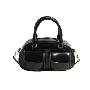 Detail of black wax leather Boston bag showing front flap pockets and glossy finish