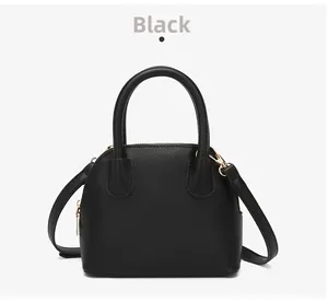 Detail of black lychee grain leather shell bag with elegant gold zipper and metal hardware