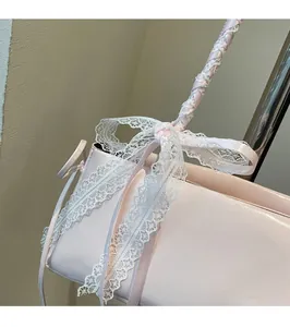 Detailed close-up of pink leather handbag featuring a delicate white lace bow decoration
