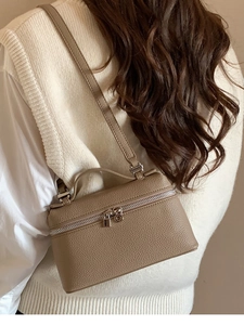Detail einer beigen Leder-Box-Tasche, getragen von einem Model für Größenreferenz