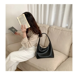 Detailansicht der schwarzen matten Hobo-Tasche mit Kieseltextur auf einem Sofa