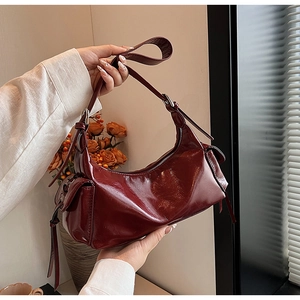 Detail shot of vintage dark red oily leather shoulder bag with chic buckles and straps