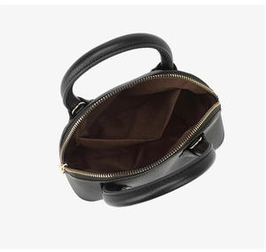 Interior detail of black leather shell bag showing double compartments and gold zipper
