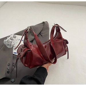 Detail view of burgundy soft leather shoulder bag with vintage texture and strap detail