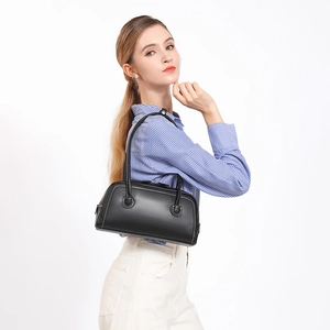 Retro black leather Boston handbag with contrast stitching worn by a model in white background