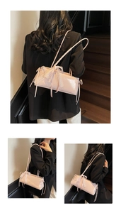 Close-up of pink glossy leather baguette bag with lace trim and satin bow detail