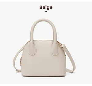 Close-up of beige shell handbag with lychee pattern leather and gold metal hardware