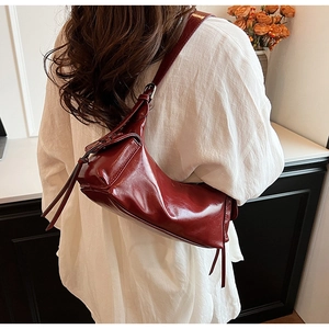Detail view of deep red vintage shoulder bag with long fringe and soft leather texture