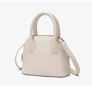 Close-up of litchi texture on beige shell bag with sleek gold-toned metal hardware