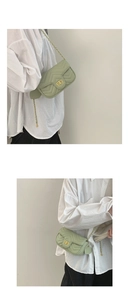 Detail of light green quilted crossbody bag with golden chain and clasp on white shirt