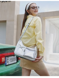 Detail of silver metallic crossbody bag featuring a bow pocket and transparent PVC slot