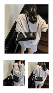 Detail of black glossy shoulder bag featuring delicate white lace bow and side drawstrings