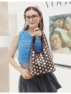 Detail of a brown leather tote bag with silver studs and punk style in outdoor setting