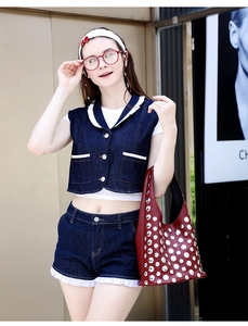 Detail of burgundy tote bag with silver star studs paired with denim vest and shorts set