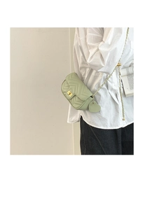 Detail of light green crossbody bag with V-quilt pattern and heart charm accessory