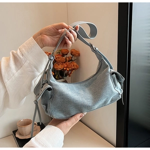 Detailed close-up of light blue denim shoulder bag with side pockets and leather strap